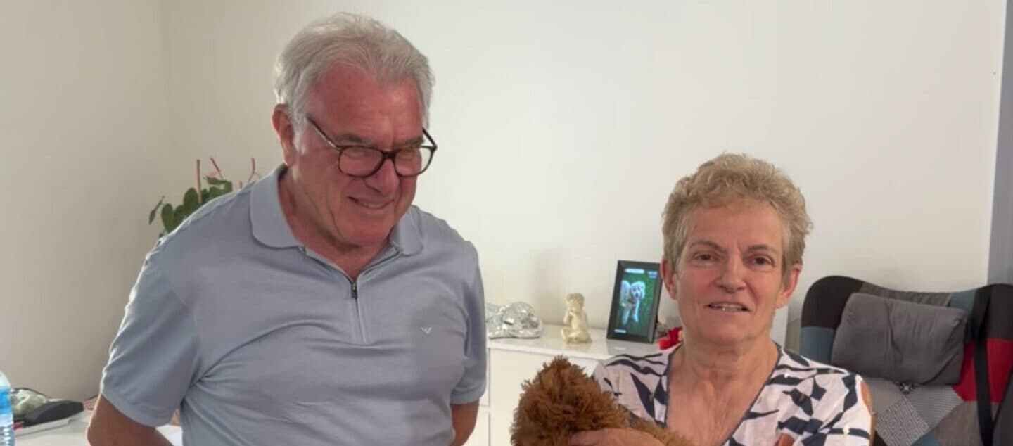 Un homme et une femme souriants assis dans leur salon avec leur petit chien